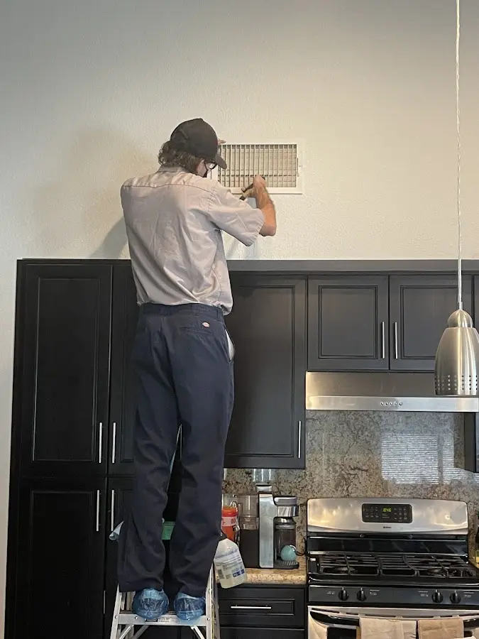 Technician inspecting an air vent during HVAC service in Cumberland
